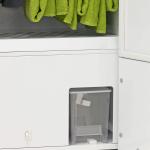 Balts apģērbu žāvēšanas skapis ar siltumsūkni, augšpusē zaļas dvieļi, apakšā caurspīdīga ūdens tvertne.