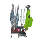 Zaļš aizsargtērps un zils apģērbs uz iekārtas, kas paredzēta mazgāšanai un žāvēšanai. Metāla rāmis ar caurulēm.