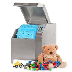 Rotaļlietu mazgāšanas un žāvēšanas mašīna ar sudraba korpusu un zilu iekšpusi, blakus mīkstā rotaļlieta un krāsainas kub